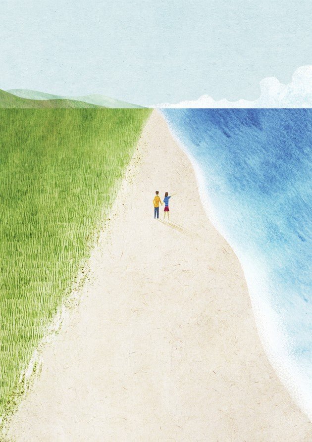 Two people standing on a sandy path between a grassy field and a blue sea. framed